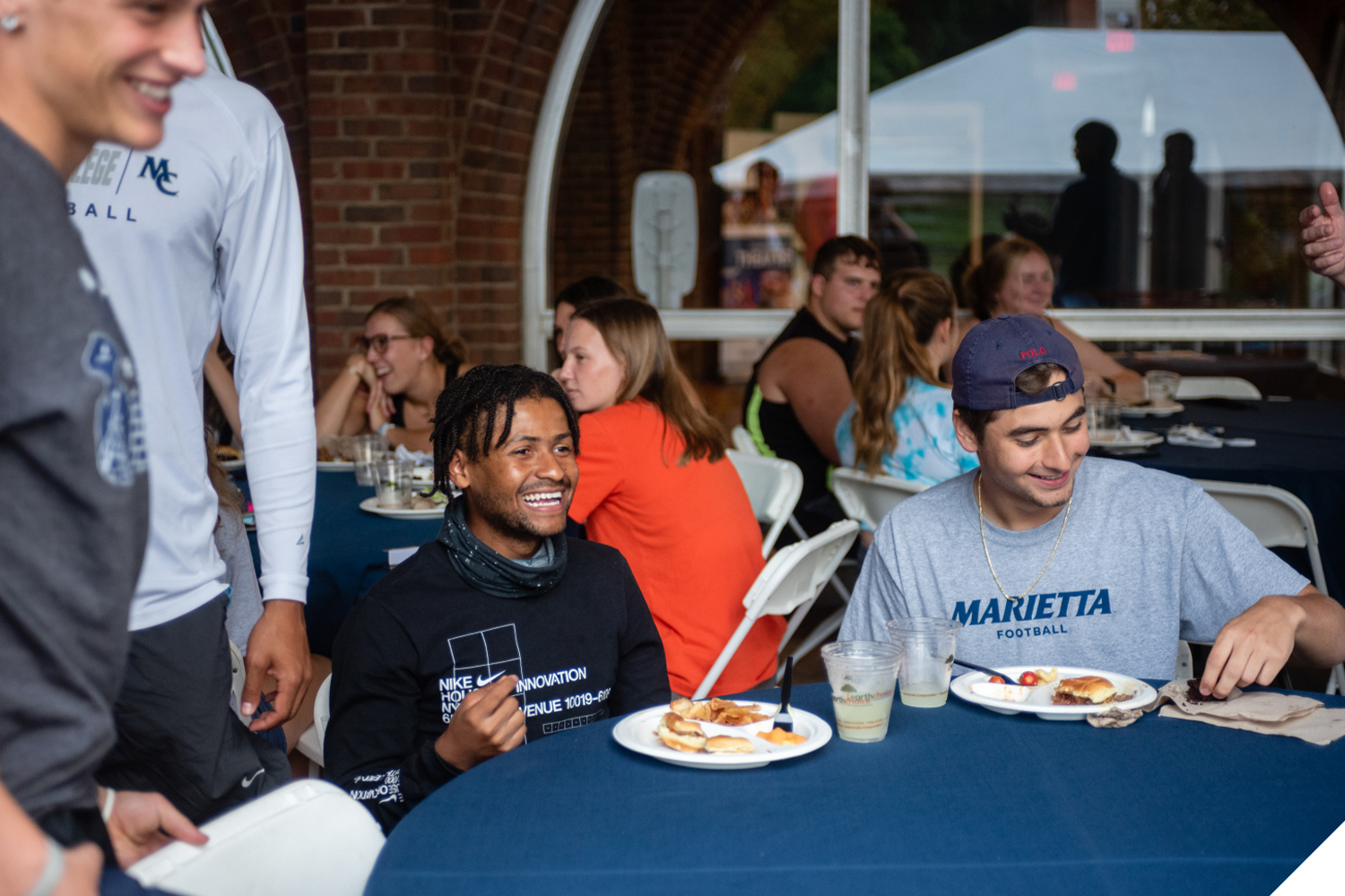 A Marietta College student laughs while sitting at a table with other students