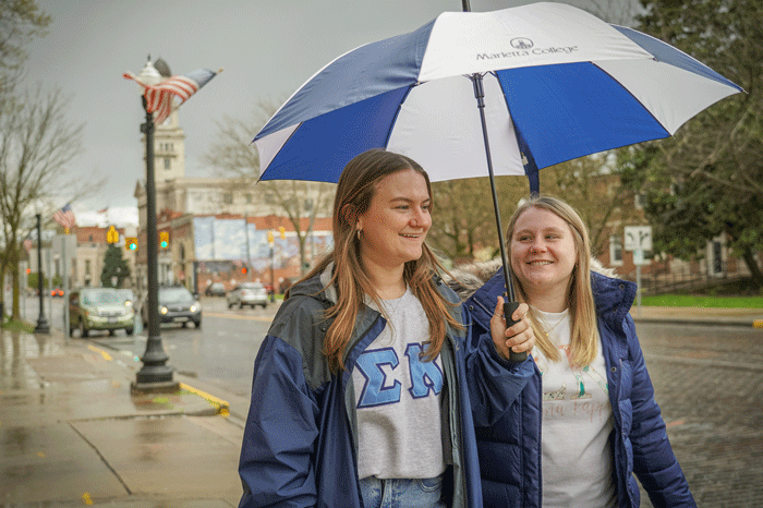 Students walking downtown under an umbrella