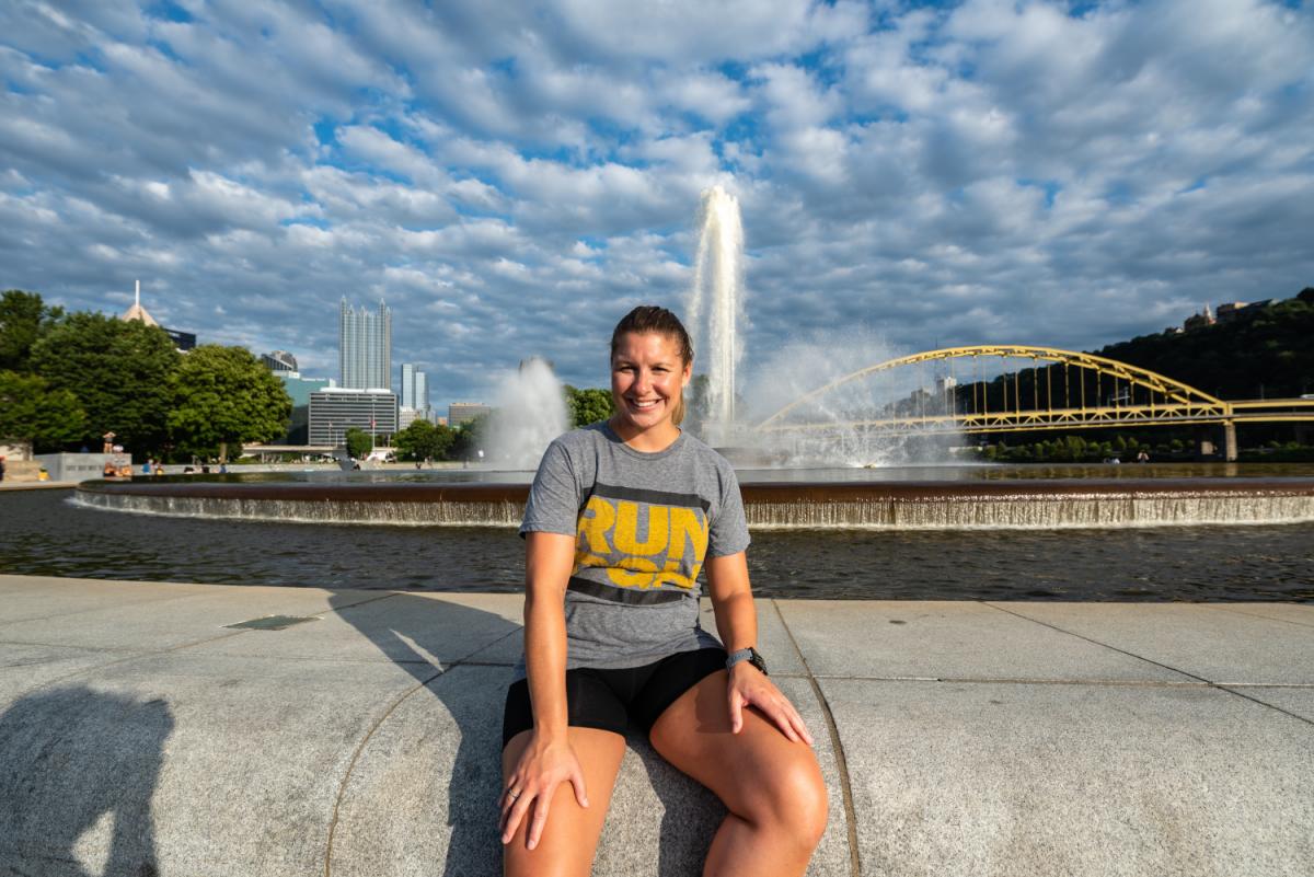 Amanda Hardt '13 sits with the Pittsburg skyline behind her