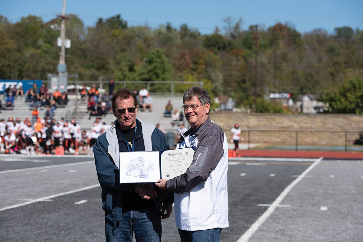 Jon Wendell '69.5 accepts and award from President Ruud on the football field