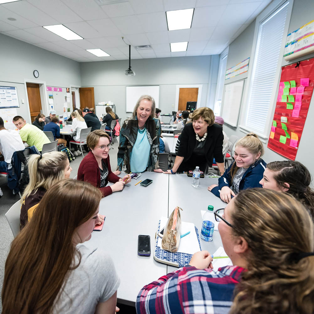 Dottie Herb and Carole Hancock talk with a table of students in their Marietta College classroom