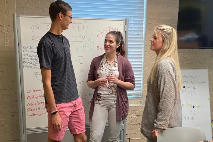 Two students speaking with an alumna