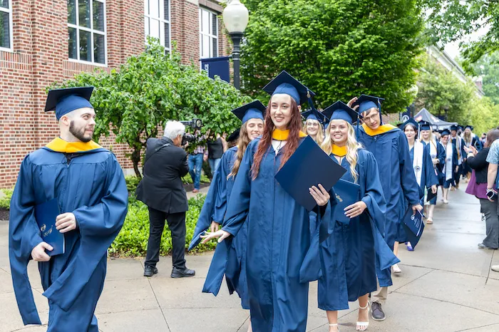 Marietta College graduates smiling during procession following Commencement.
