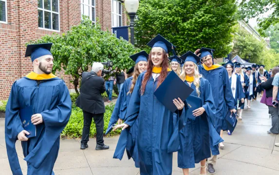 Marietta College graduates smiling during procession following Commencement.
