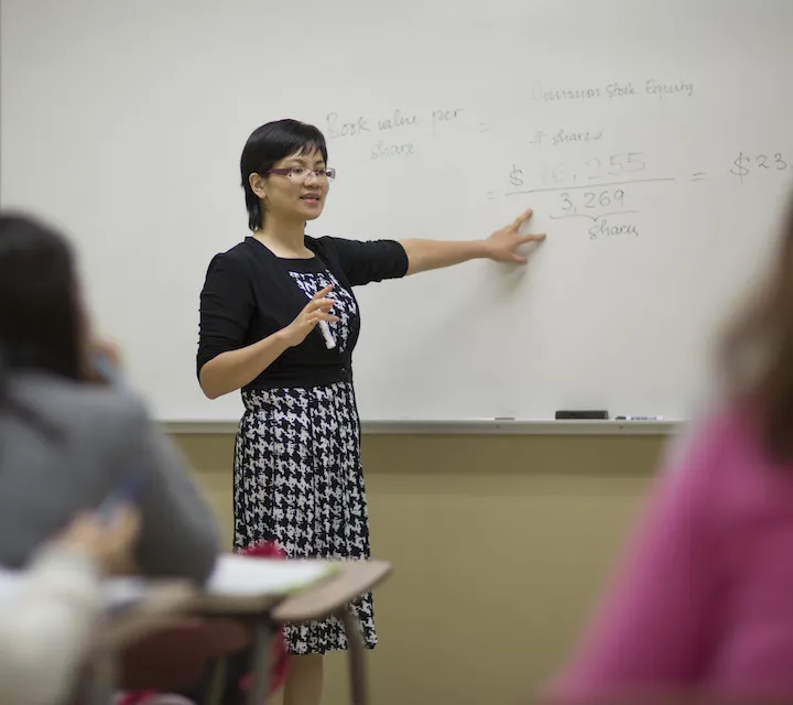 Professor Duong Le standing at a whiteboard while teaching a finance class.