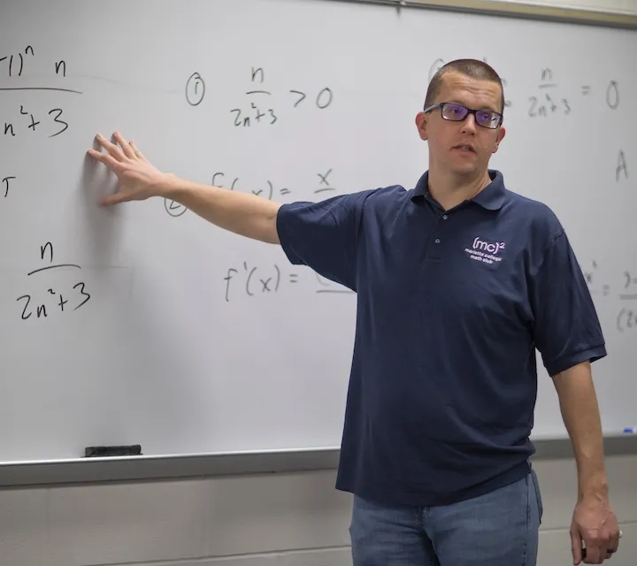 Marietta College Mathematics Professor John Tynan points to the whiteboard while giving a lecture.