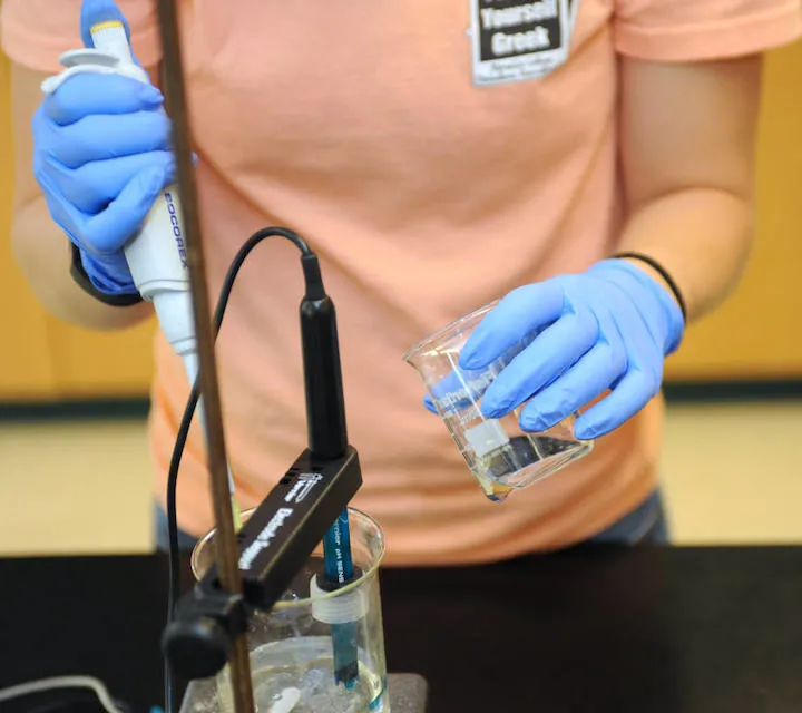 A Marietta College Industrial/Engineering Chemistry Major holds a beaker and a dropper