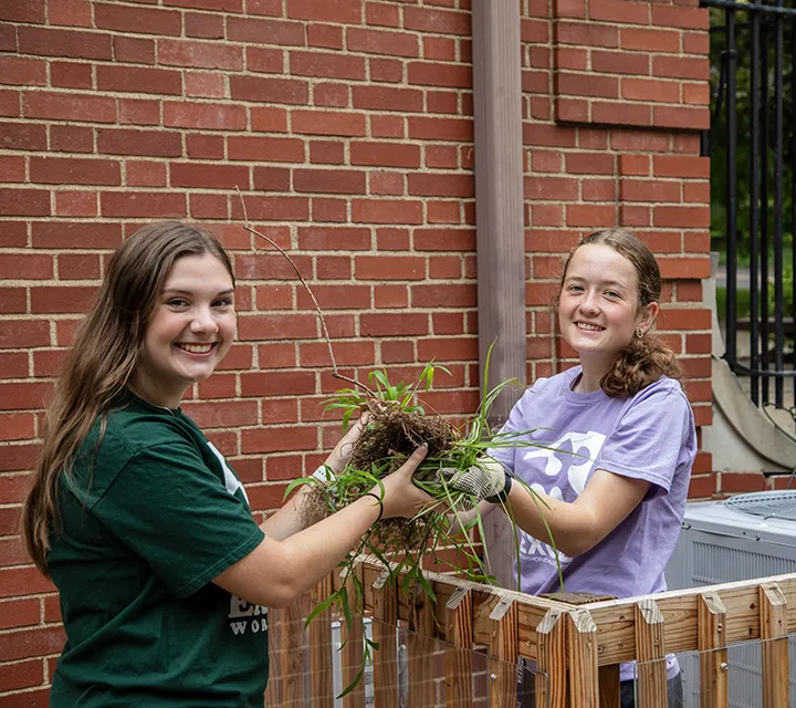 Two Marietta College McDonough Leadership Program students pull weeds at the Betsy Mills during the EXCEL program's service project