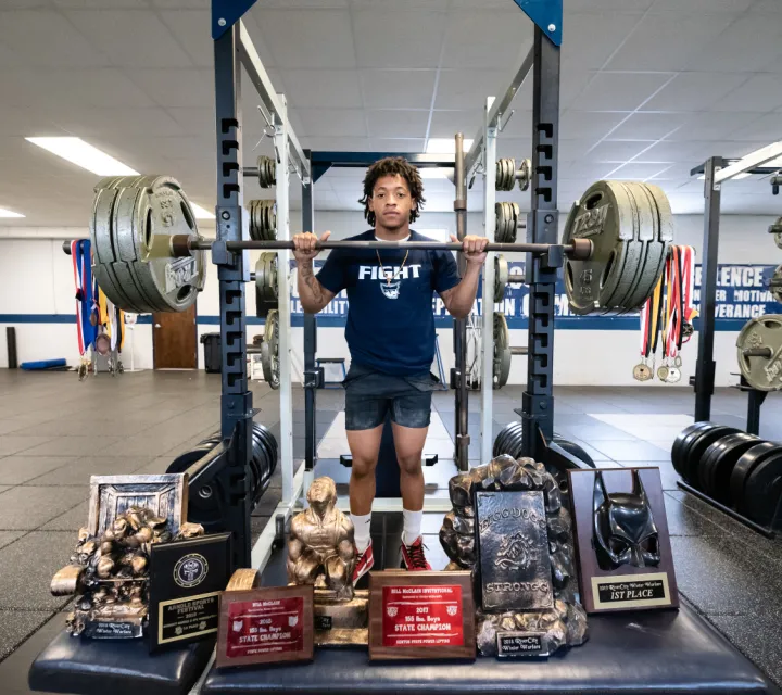 TJ King '22 in front of all of his power lifting awards