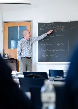 Professor Kevin Pate points to a chalkboard during a Biochemistry class.