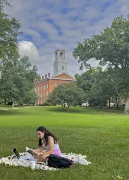 An english major studies while sitting in the grass outside Erwin Hall on the campus of Marietta College