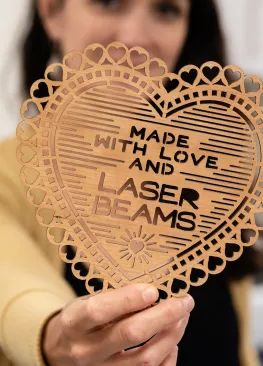 Graphic design professor Sara Rosenstock holds a wood cutout that reads MADE WITH LOVE AND LASER BEAMS