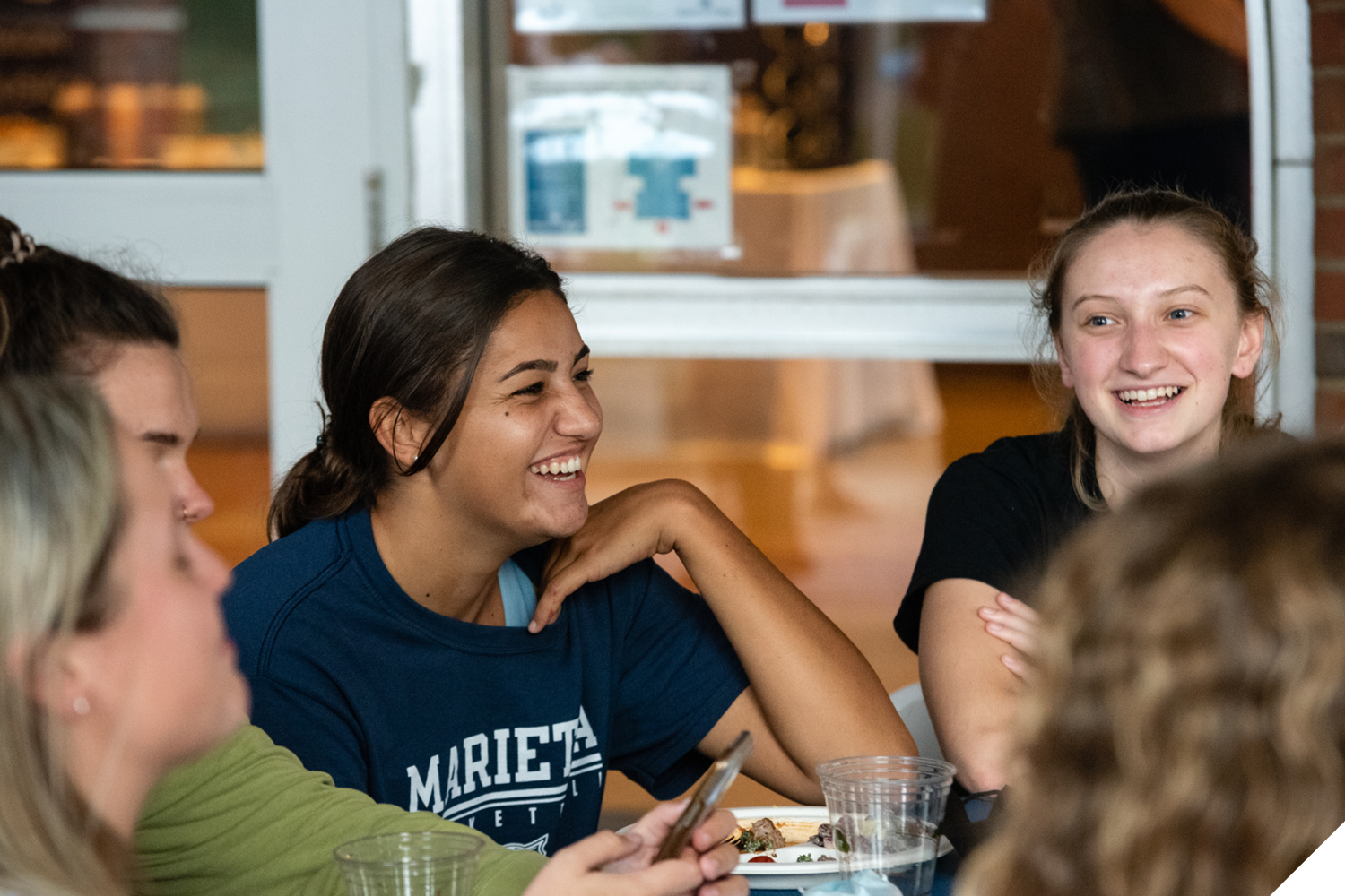 A Marietta College student laughs while sitting at a table with other students