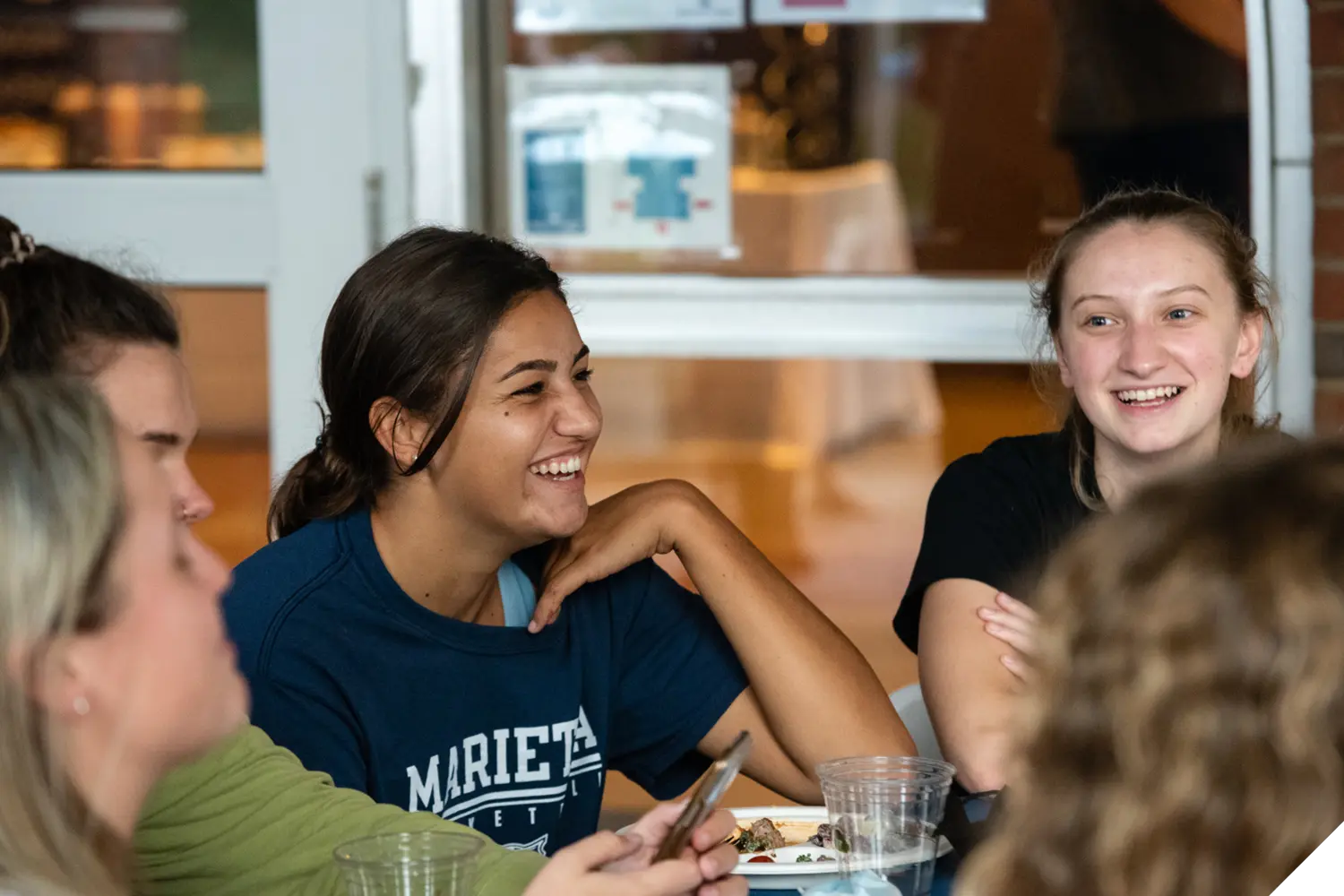 A Marietta College student laughs while sitting at a table with other students