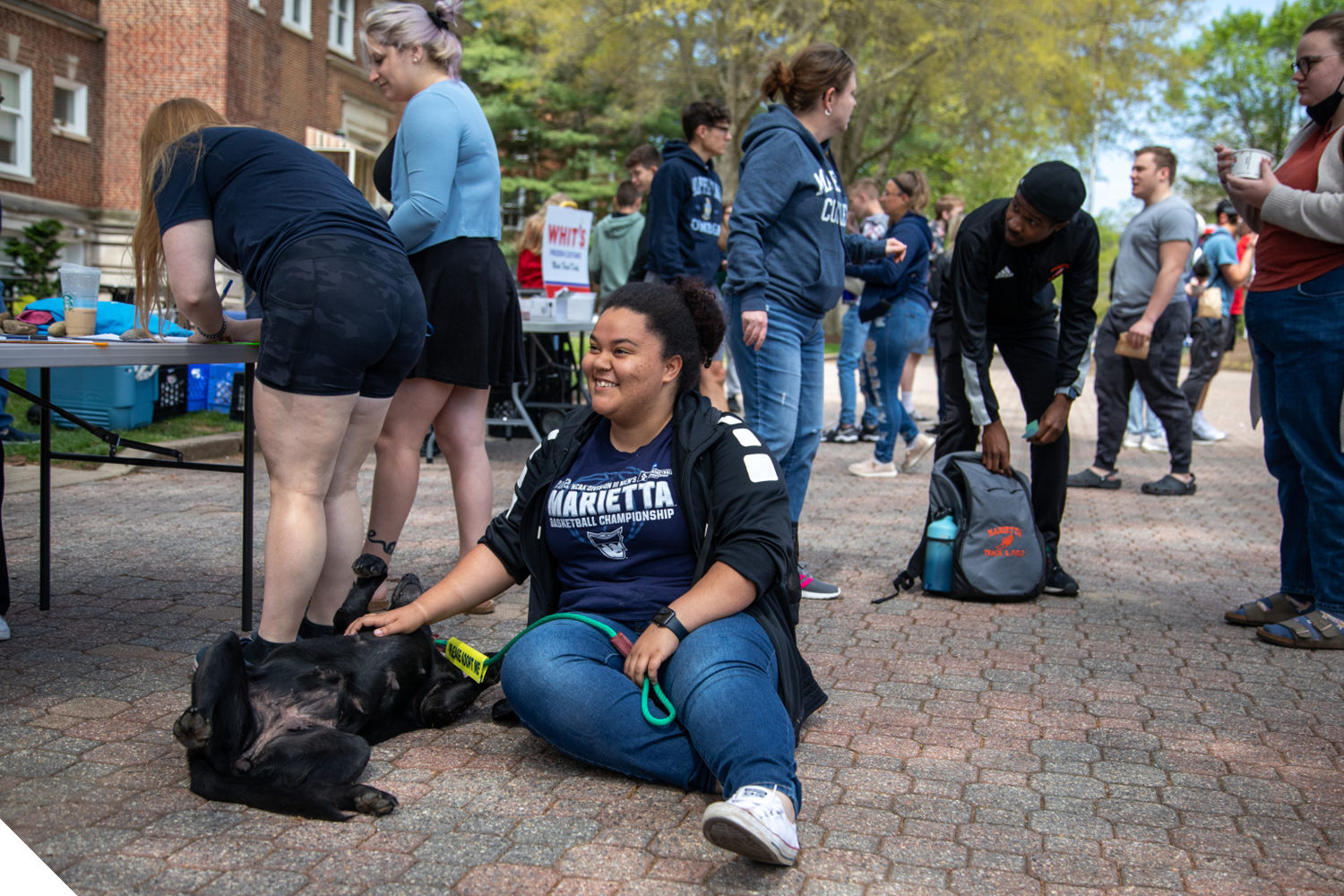 A Marietta College student smiles while petting a dog during a Feel Good Friday event