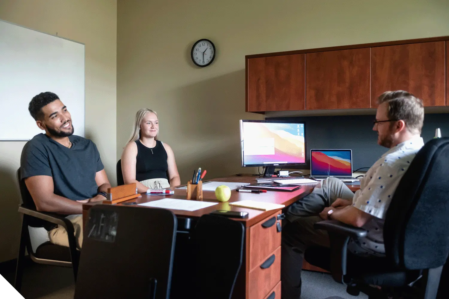 Two students speaking with a professor during office hours.