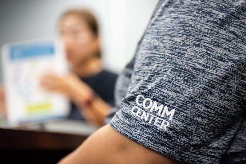 Detailed shot of shirt sleeve which reads "COMM CENTER"