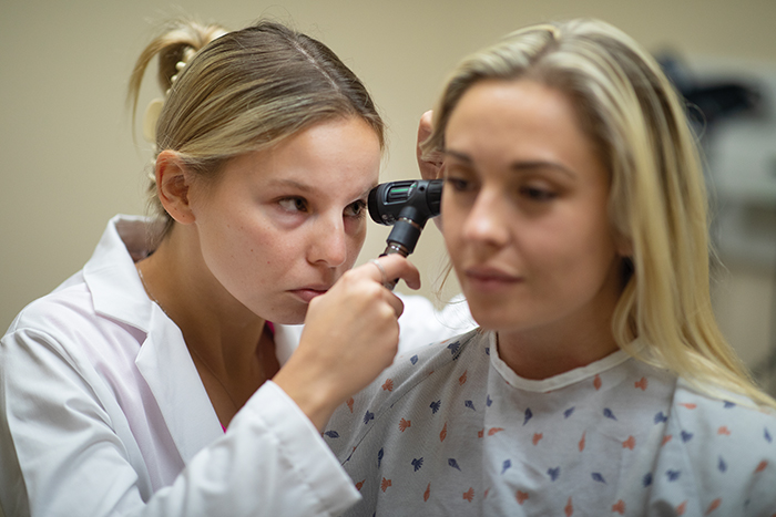 Graduate students Katie Stomski PAâ25 (left) and Chelsey Ward PAâ25 practice patient exams in one of the clinical rooms in the Physician Assistant Studies Building.