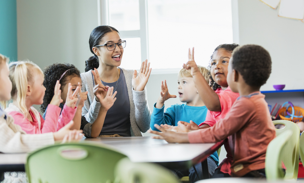 a teacher counting on fingers with young students