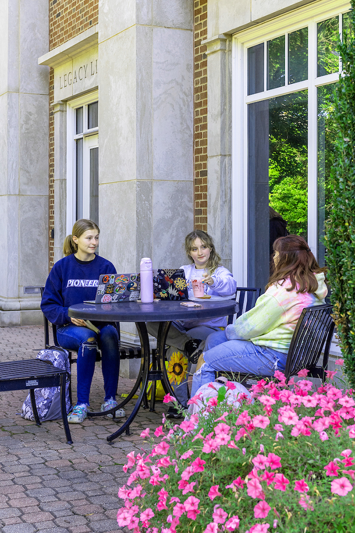 Three girls chat at a Cafe table