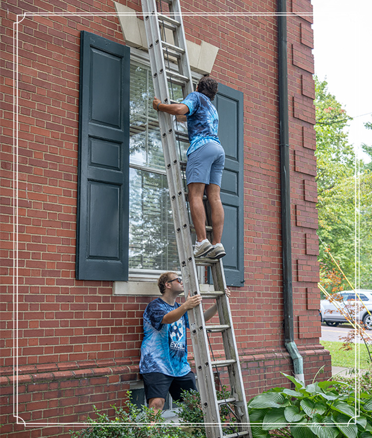 two students cleaning windows at local nonprofit organization