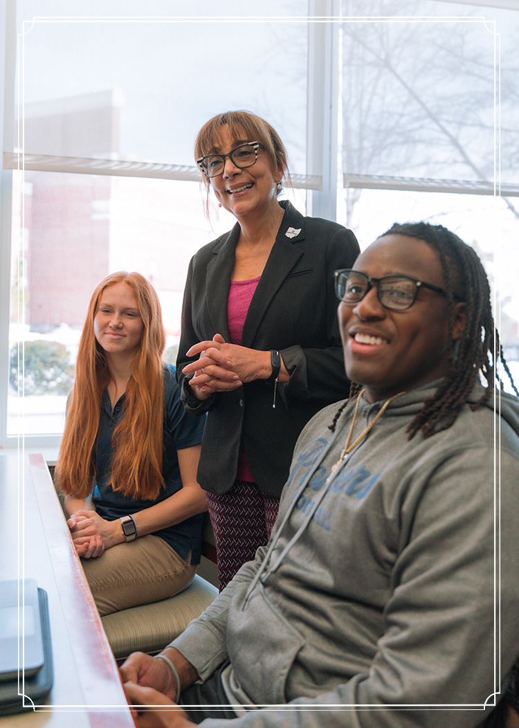 Two students and a professor meet in the Milone Center in the library