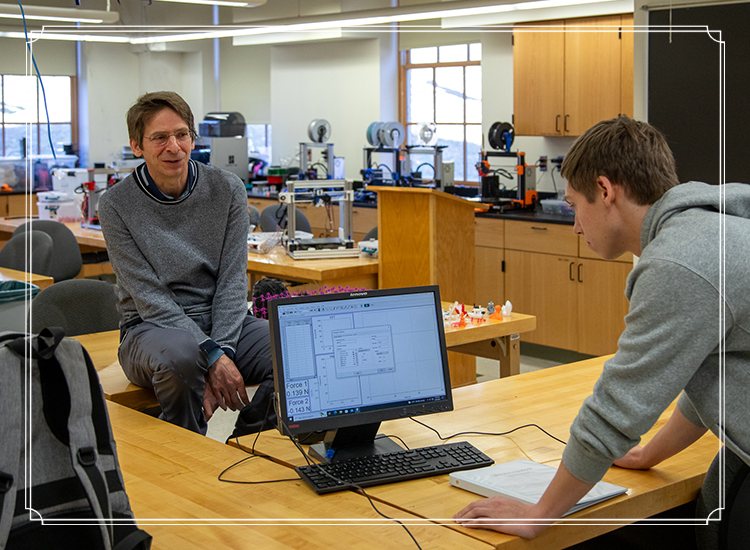 Dr. Craig Howald consults with physics student doing reseach on computer