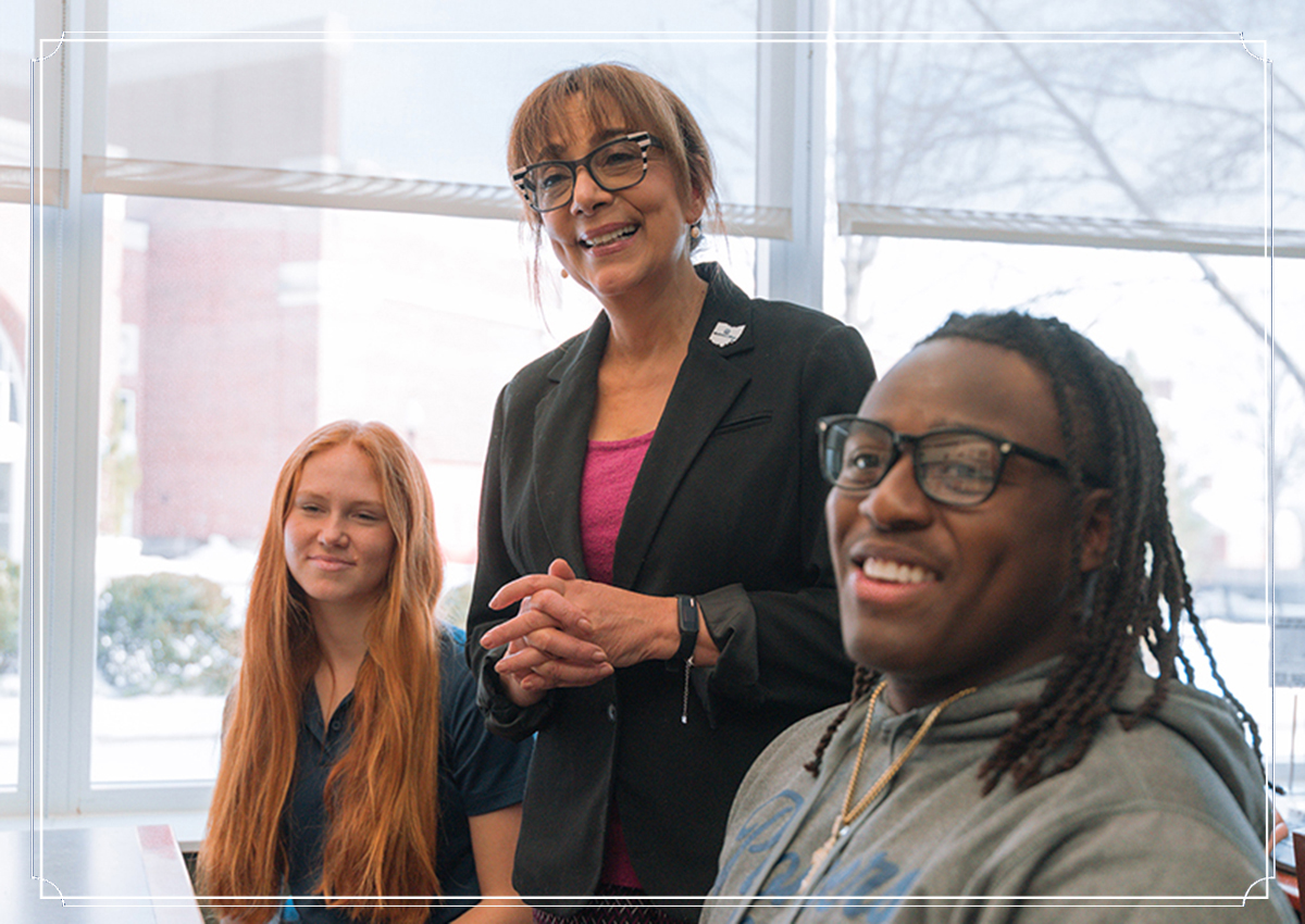 Professor stands alongside two students in student success center