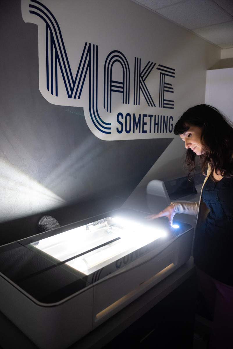 A Marietta College professor supervises a laser cutting machine