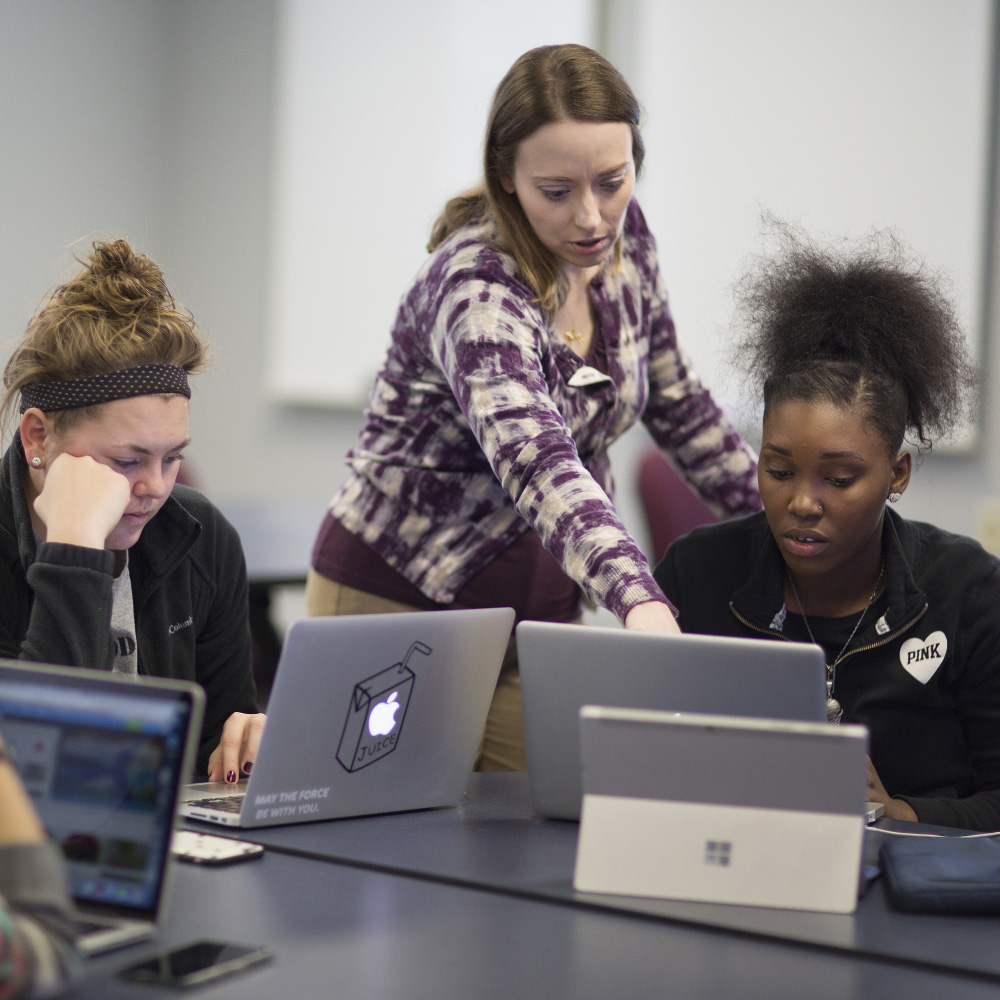 A student helps another on their computer