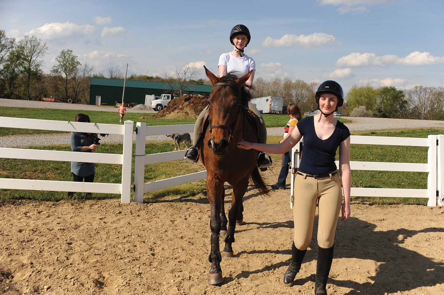 A Marietta College student leads a horse with another MC student riding it