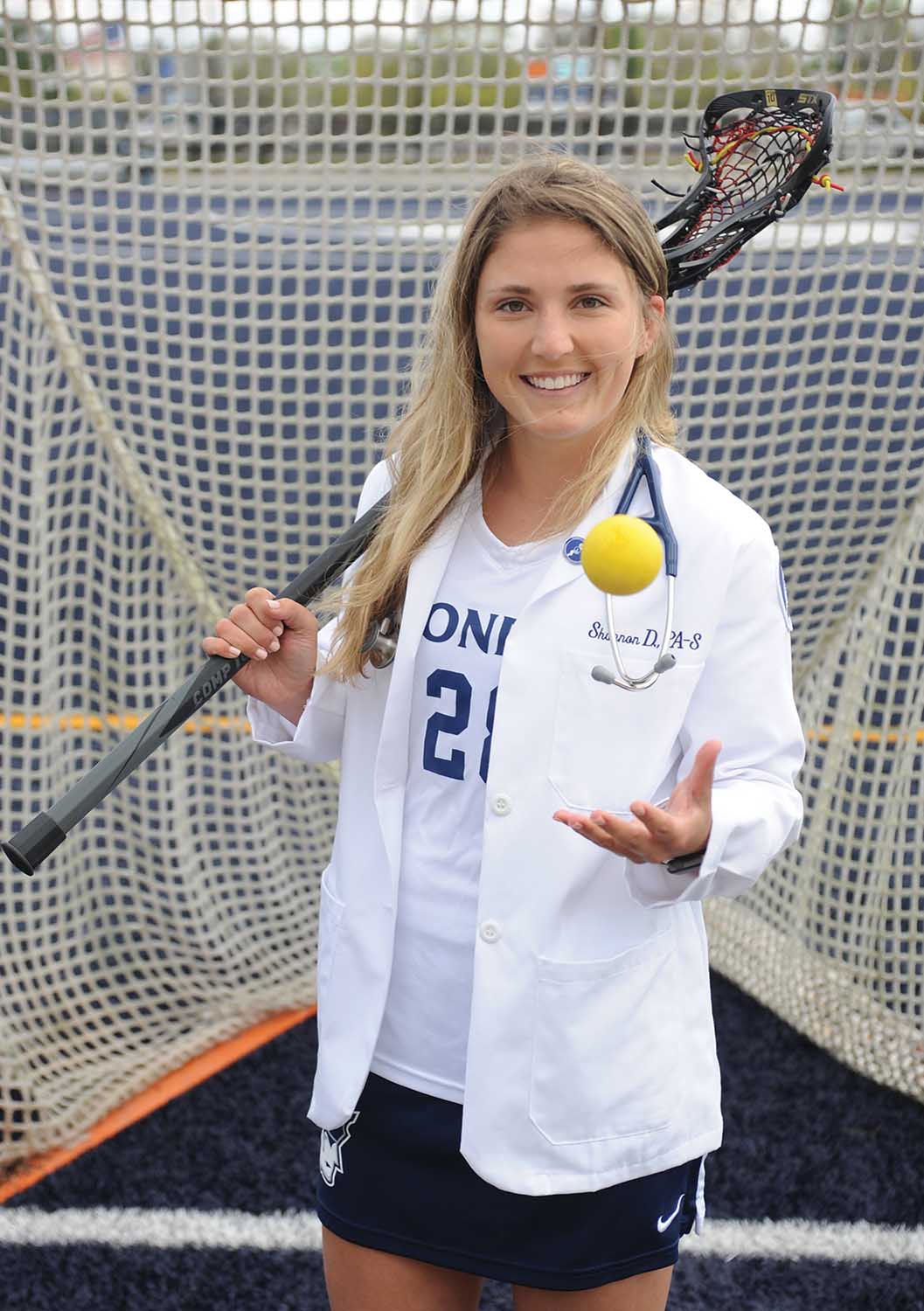 Shannon Doyle PA '22 poses in front of a Lacrosse goal in her PA white jacket