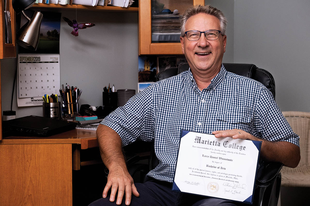 Larry Wisniewski '78 holding the diploma he finally recieved after over 40 years