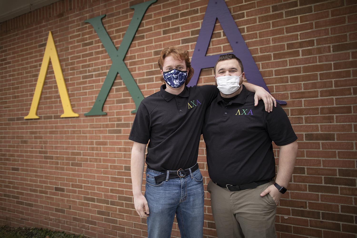 Two Marietta College Students stand in front of the Lambda Chi Alpha Sign