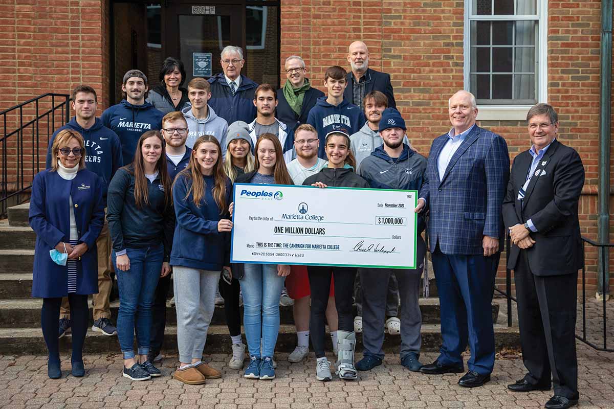 A group of Marietta College students and employees stand for a photo with a donation check