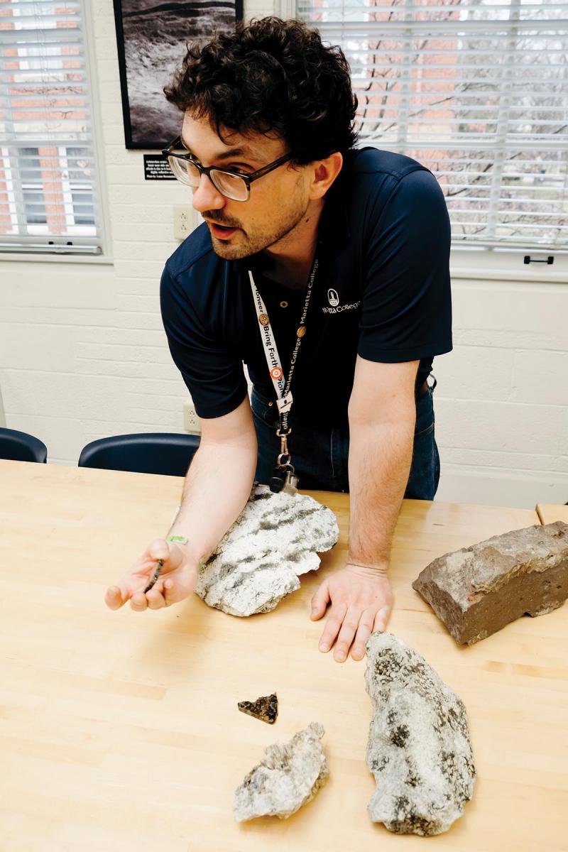 Andrew Beck leans on a table full of rocks
