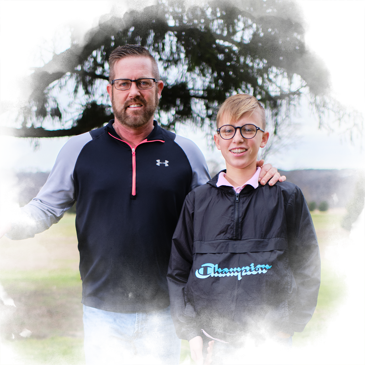 Shawn Shuster '98 stands holding a golf club with his son