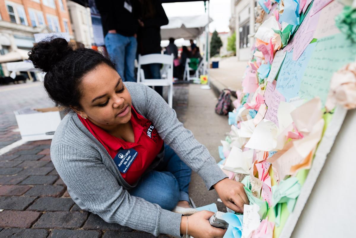 Marietta College Student works on a collage at the first Brick Street Bash