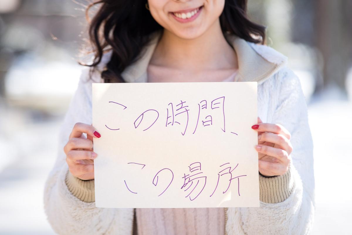 An International Student holds up a written sign
