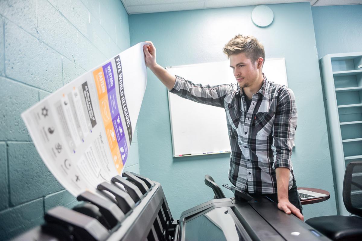 A Marietta College student pulls his poster out of the printer at the Communication Resource Center