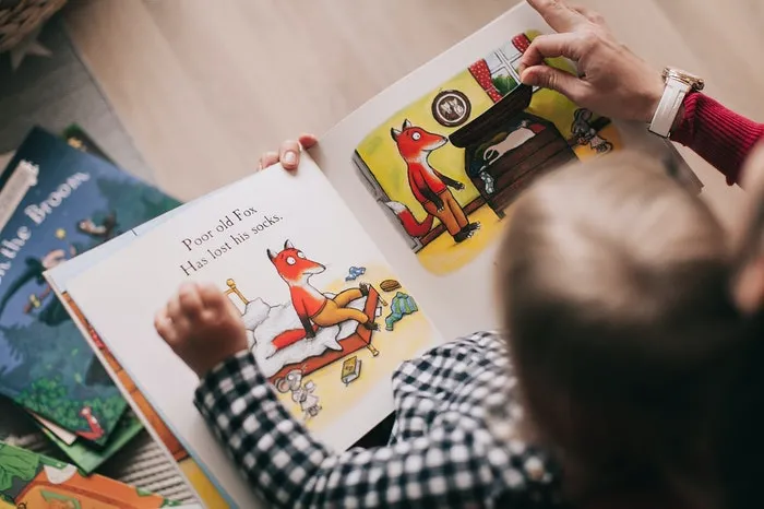 Child reading a book with an adult