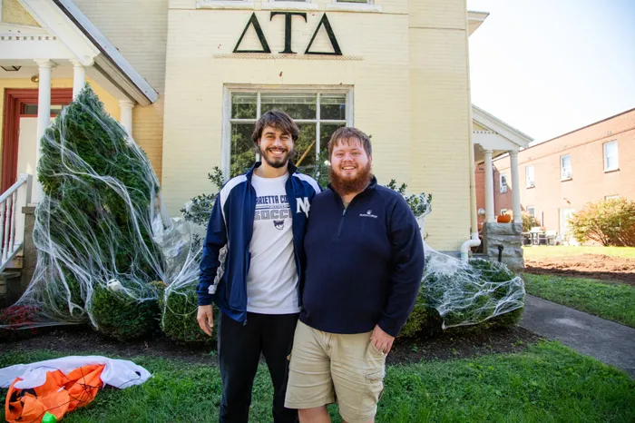 Two male students in front of Delta Tau Delta house