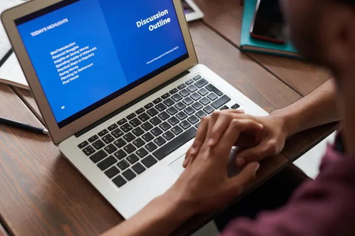 Open laptop with hands folded on the keyboard