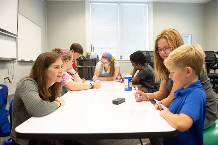 Faculty and students working with young kids in classroom