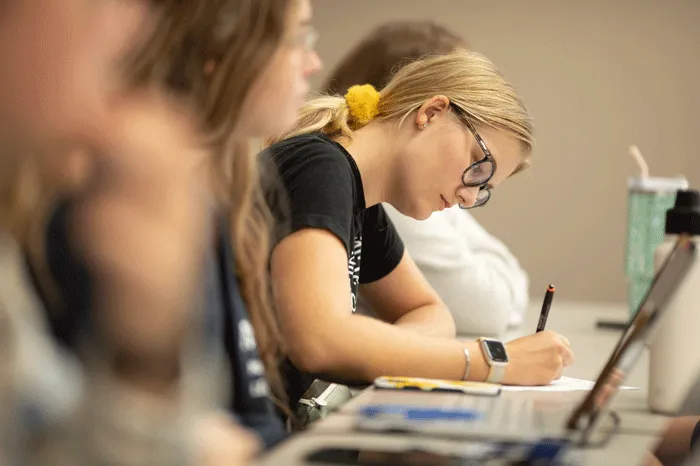 Female student writing at a desk