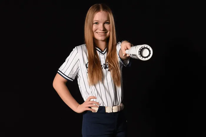 Softball player pointing with a bat