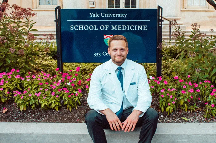 Brendan Adkinson sitting in front of the Yale University School of Medicine