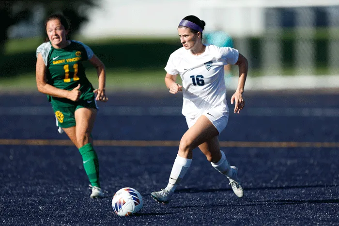 Women's soccer player runs away from a defender