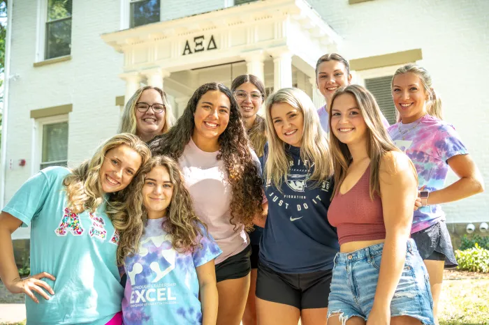 Alpha Xi Delta members standing in front of the renovated sorority house.