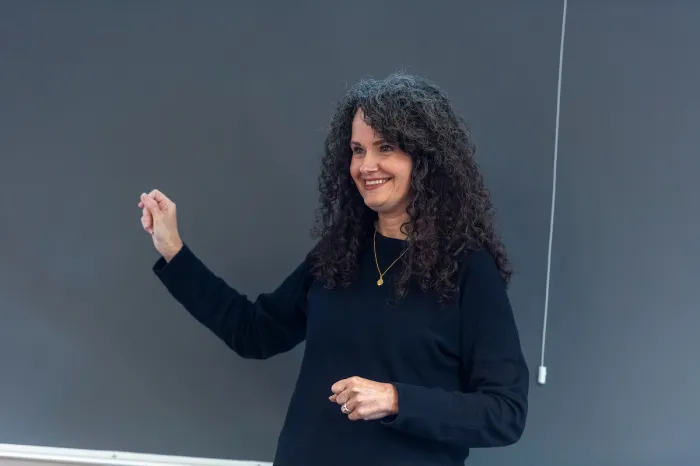 Marietta College Professor stands next to chalkboard
